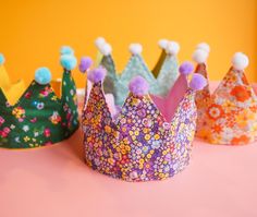 three colorful crowns sitting on top of a pink table