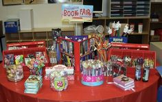 there is a red table with many items on it and a sign that says book fair