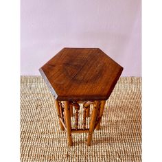 an octagonal wooden table with four legs and a small square top on a woven rug