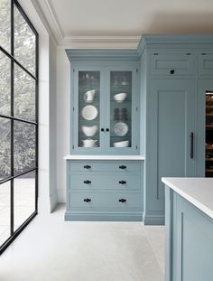 an empty kitchen with blue cabinets and white counter tops, along with black framed glass doors