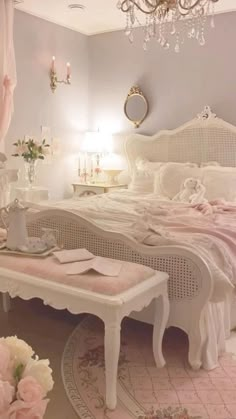 a white bed sitting in a bedroom next to a table with flowers on top of it