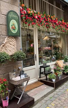 a flower shop with lots of flowers in the window and on the side of the building