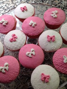 cupcakes decorated with pink and white icing are on a glass platter