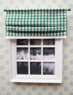 a window with a green and white checkered valance hanging on the side of a wall