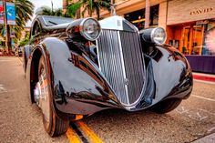 an antique car is parked on the side of the road in front of a store