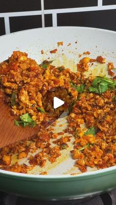 a pan filled with food and a wooden spatula on top of the stovetop