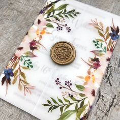 a button sitting on top of a flowered cloth with leaves and flowers around it