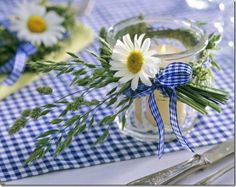 a vase filled with flowers sitting on top of a blue and white checkered table cloth