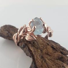 a close up of a ring on top of a piece of driftwood with leaves