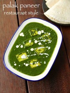 palak paneer restaurant style is served in a bowl with pita bread on the side