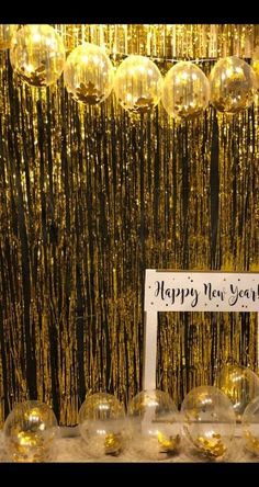 a happy new year sign surrounded by gold streamers and hanging balloons in the background