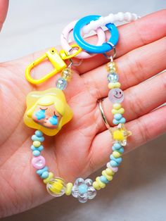 a person is holding some colorful beads in their hand and there are two charms attached to them