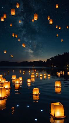 many lanterns floating in the water at night