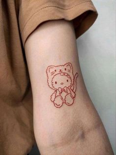 a small red teddy bear tattoo on the left side of the right arm and shoulder