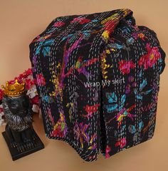 a black and multicolored bag sitting on top of a table next to a statue