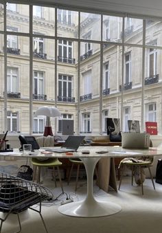 a room filled with lots of windows and furniture in front of large glass windows that look out onto the street