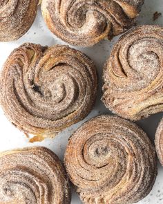 several cinnamon rolls on a white surface with powdered sugar sprinkled on top