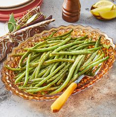 green beans in a glass bowl with a yellow handled knife next to it on a table