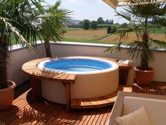 a hot tub sitting on top of a wooden deck next to a palm tree and potted plants