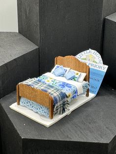 a miniature bed made out of books on top of cement blocks