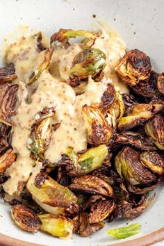 a white bowl filled with brussel sprouts covered in gravy