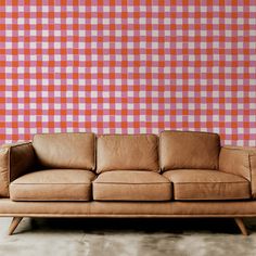 a brown leather couch sitting in front of a checkered wall