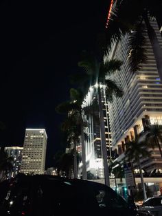 a city street at night with tall buildings and palm trees