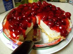 a large cake with cherries on top is being cut by a knife from the side