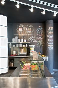 a restaurant with chalkboard menus on the wall and food in trays at the counter