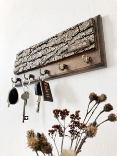 a bunch of keys hanging on a wall next to a vase with flowers in it