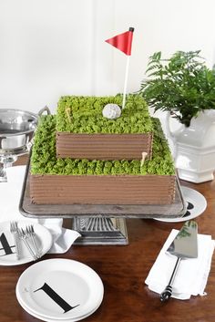 a golf themed cake on a table with plates and silverware in the foreground