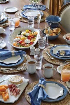 a wooden table topped with plates and cups filled with food