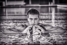 a man is swimming in the water with a ball and holding it up to his face