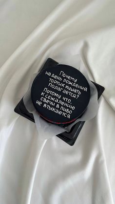 a black and white object with words on it sitting on a white cloth covered surface