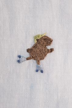 a close up of a small embroidered animal on a white piece of cloth with blue feet