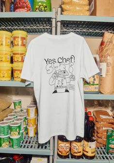 a t - shirt that says yes chef on it in front of shelves with food