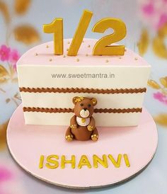 a teddy bear sitting on top of a pink and white cake with the number 12 on it