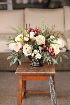 an arrangement of flowers on a table in front of a couch