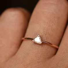 a woman's hand with a gold ring and a diamond in the shape of a heart