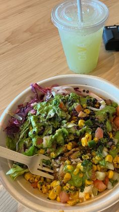 a white bowl filled with salad next to a drink