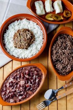 bowls filled with rice, beans and meat on a mat next to utensils