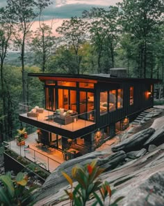 a modern house on top of a cliff overlooking the trees and mountains at sunset or dawn