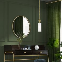 a living room with green walls and a gold mirror on the wall, a black chair in front of it