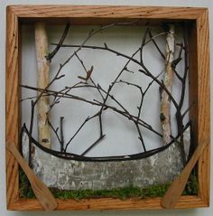 a wooden frame with branches in it and moss growing on the bottom part of the frame