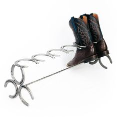 a pair of cowboy boots hanging from a hook on a shoe rack with two pairs of scissors