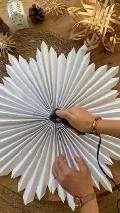 a person holding a white paper fan on top of a table