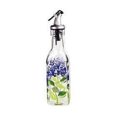 a glass bottle with blue flowers painted on the side and a metal faucet