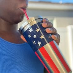 a woman drinking from a red, white and blue cup with an american flag on it