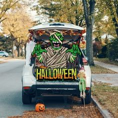 a van decorated with an image of a monster and pumpkins on the side of the road