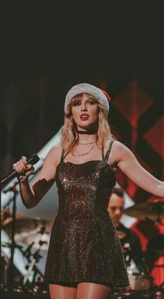 taylor swift performing on stage with her arms out in the air and holding a microphone